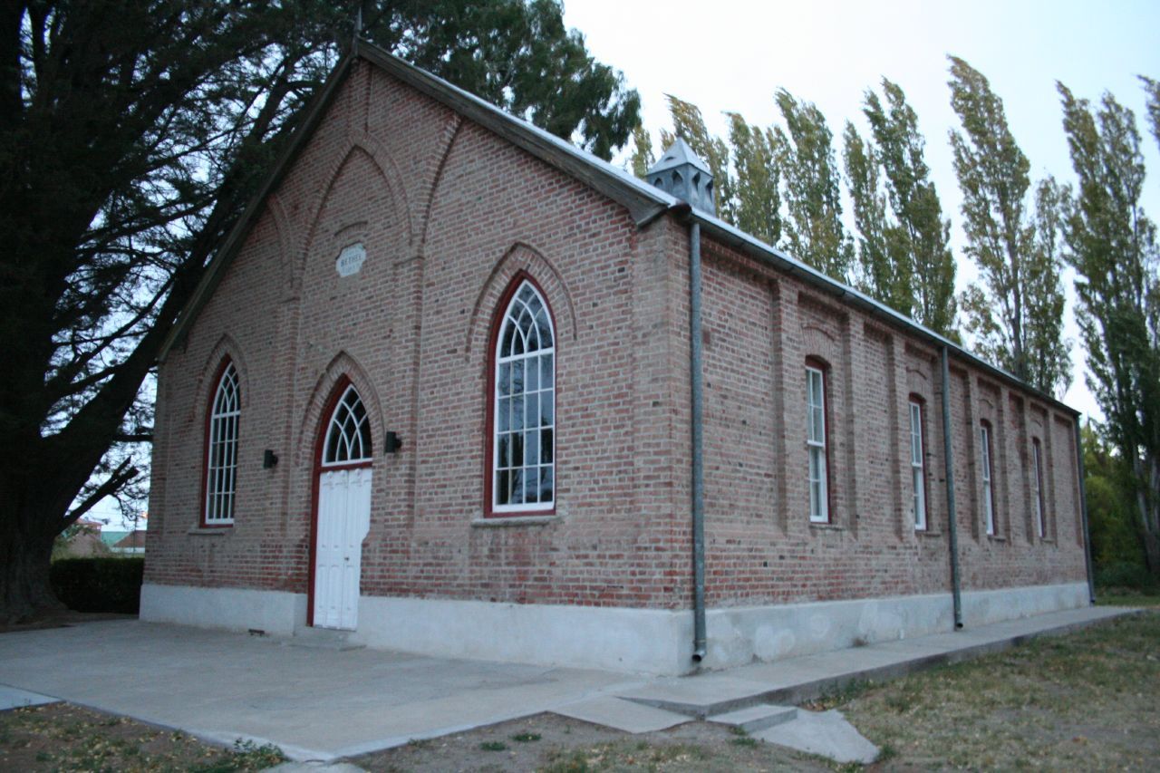 The red-brick Welsh chapel Capel Bethel at Gaiman, Patagonia, with wind-bent poplars behind