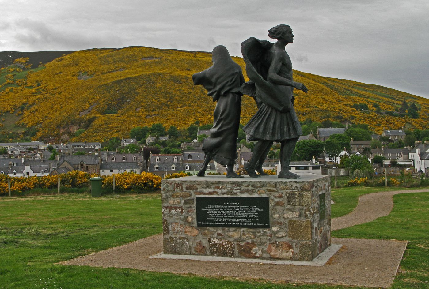 Bronze statue of an emigrant family looking out over Helmsdale village and gorse-covered hills
