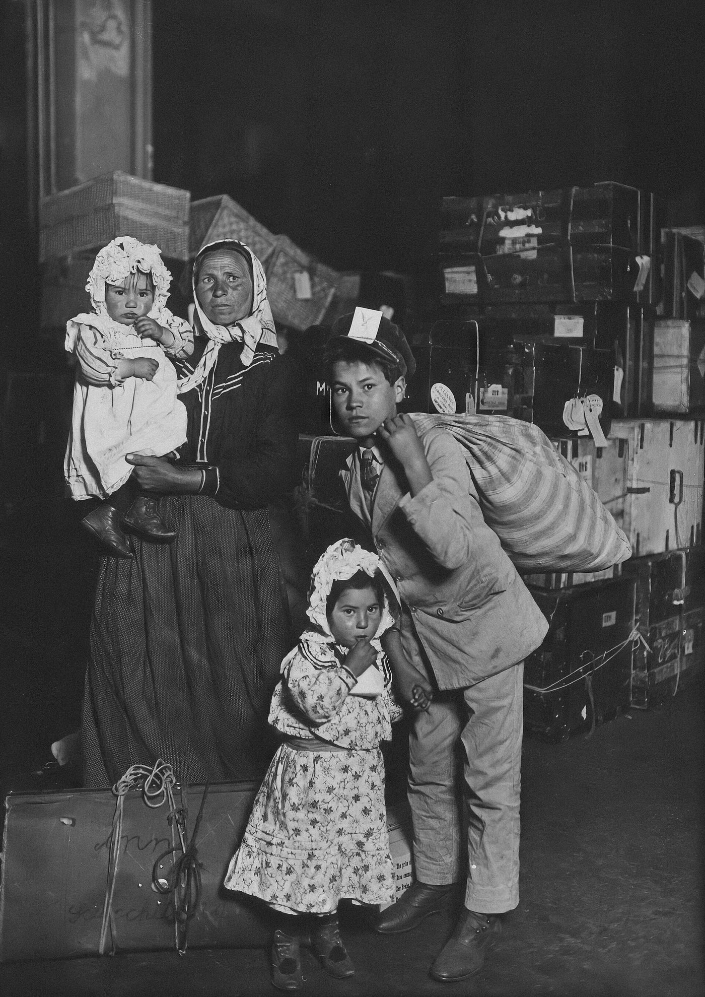 A mother and three children with their trunks in the Ellis Island baggage room, 1905